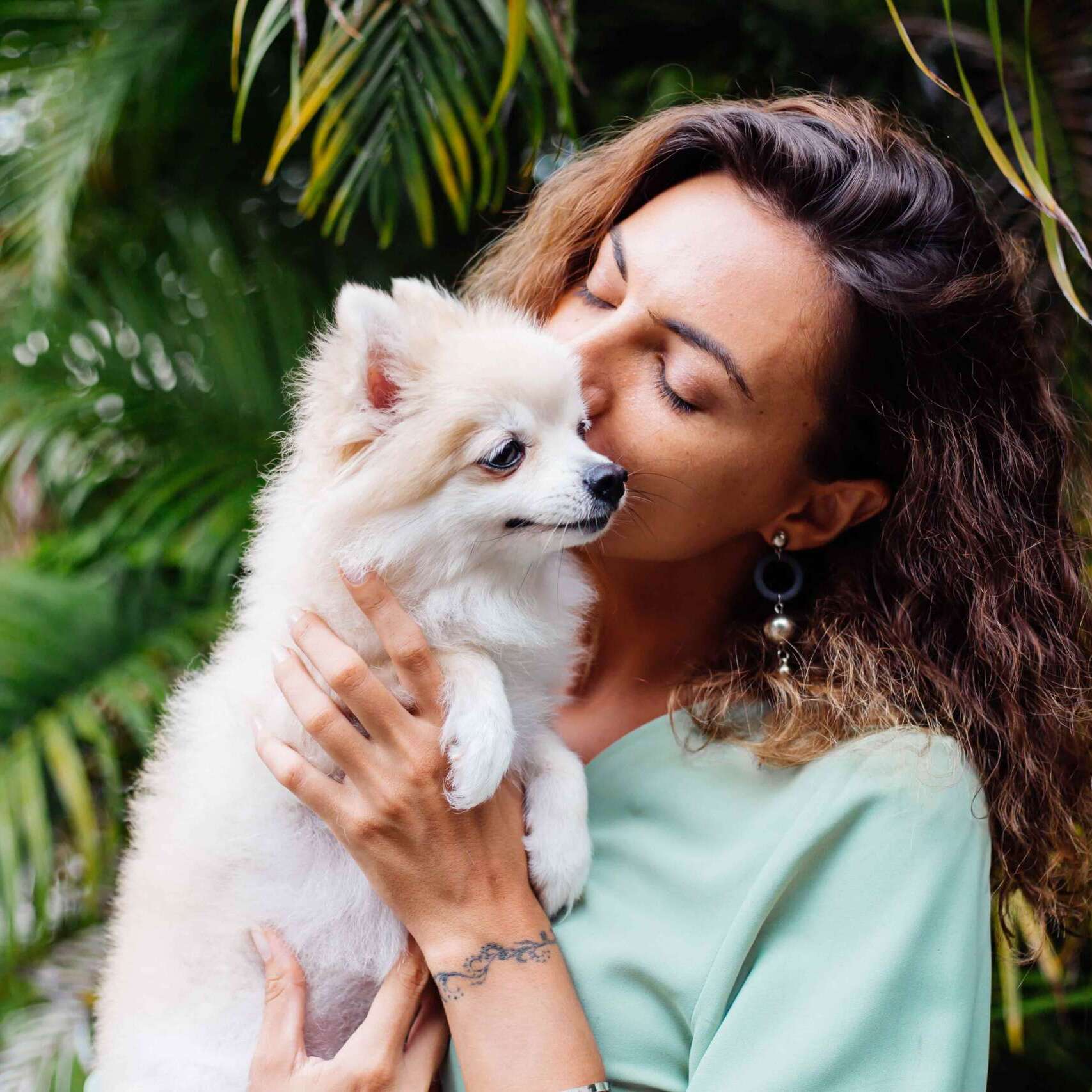 outdoor-portrait-curly-european-tanned-woman-holds-happy-pet-dog-pomeranian-spitz-min